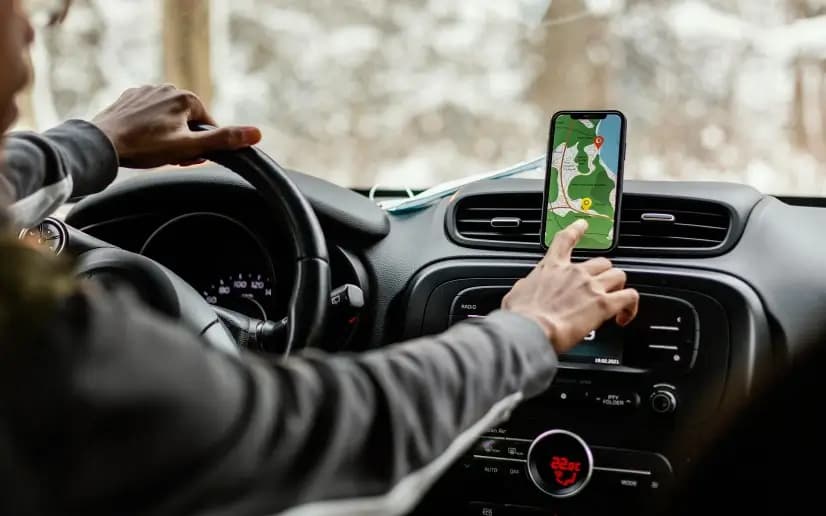 Smartphone mounted in an Uber driver's car showing navigation and ride details during peak hours