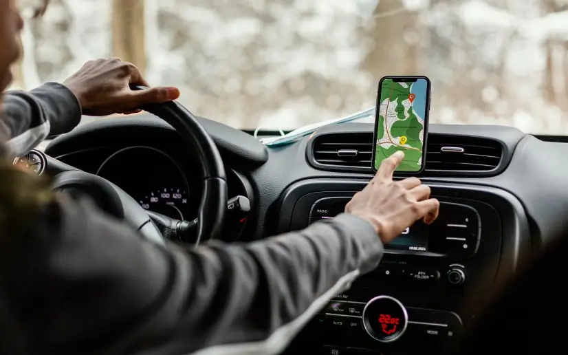Smartphone mounted in an Uber driver's car showing navigation and ride details during peak hours